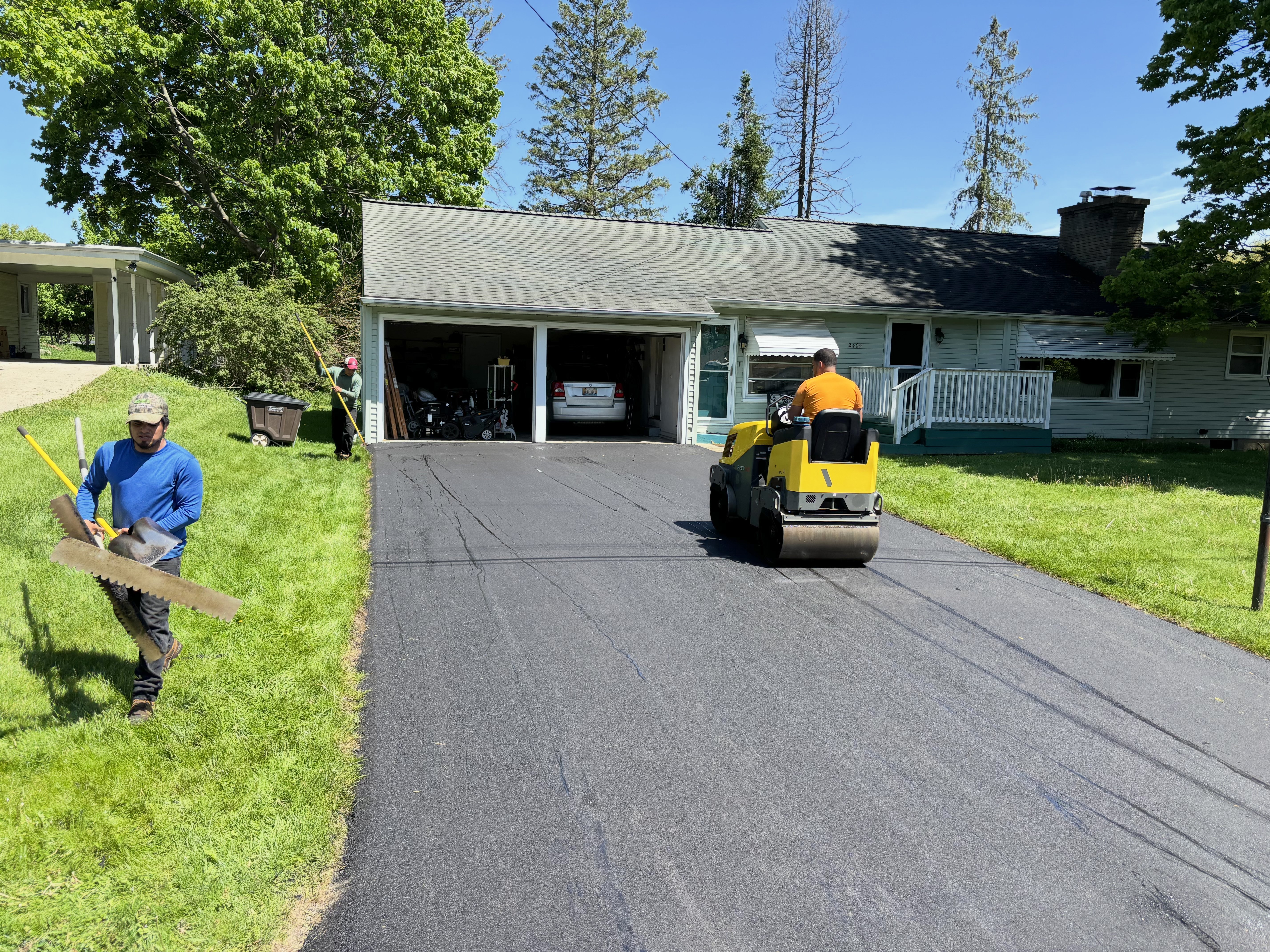Crew paving residential driveway with roller compactor in Southeast Michigan